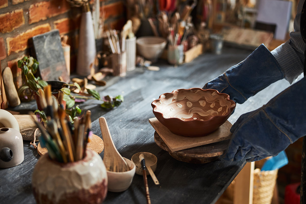 potter-hands-placing-painted-bowl-on-table-in-pott-resize.jpg